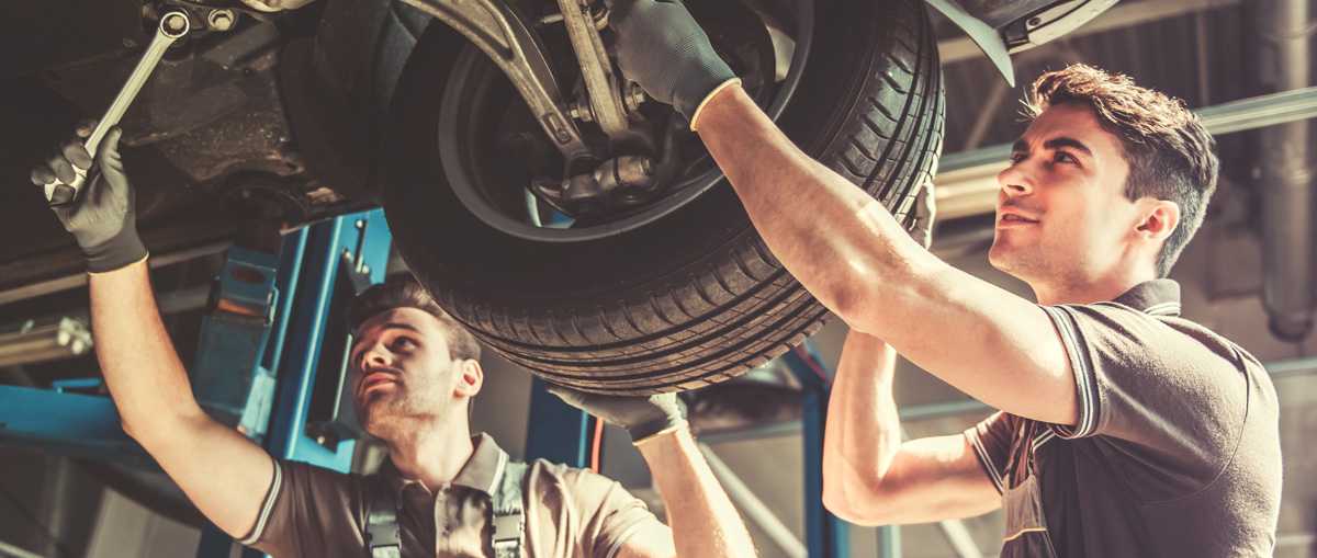 Two Mechanics Working Under A Car To Repair It